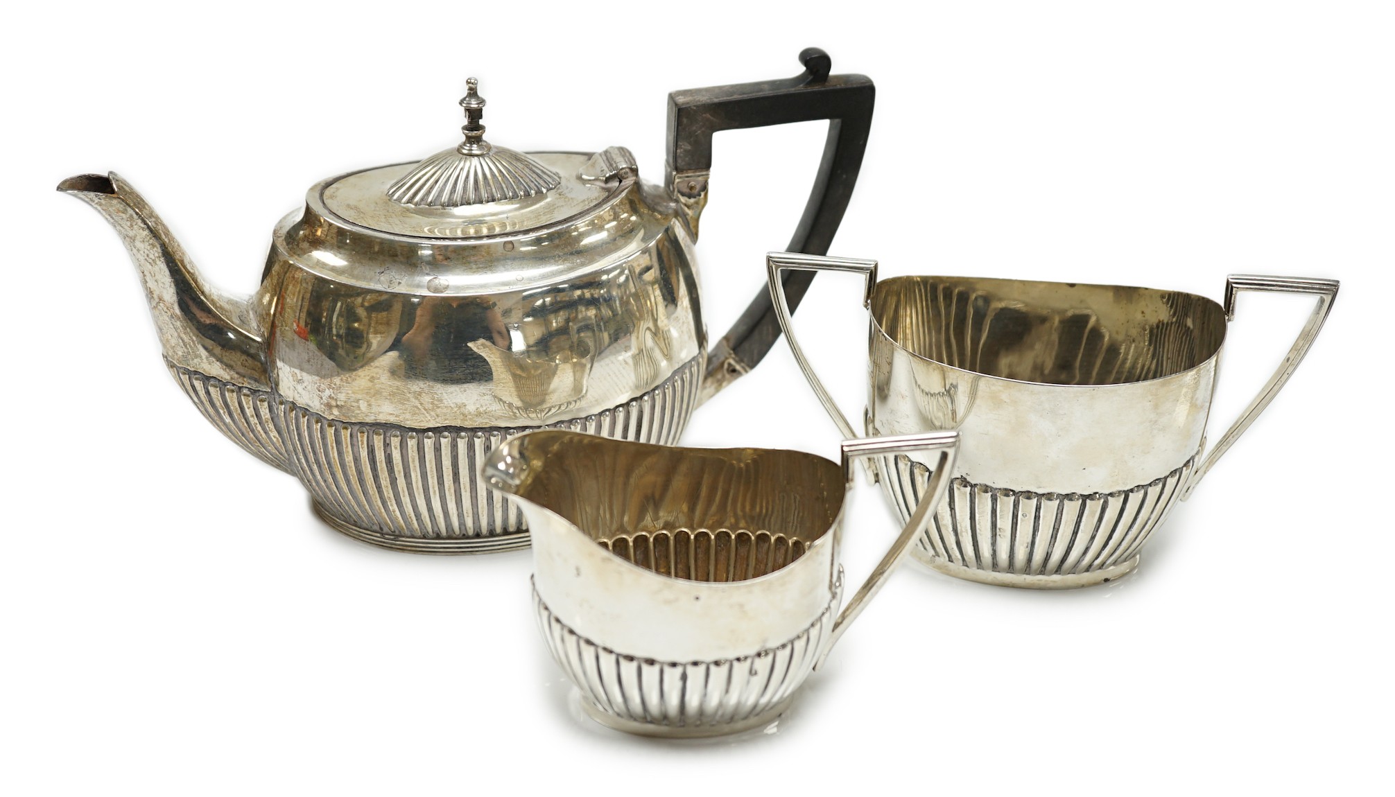 A matched early 20th century silver bachelor's three piece tea set, tea pot, James Dixon & Sons, Sheffield, 1920, cream and sugar, Walker & Hall, Sheffield, 1904, gross weight 14oz.